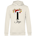 Ein cremefarbener Hoodie mit einem weihnachtlichen Design, das den Buchstaben "I" zeigt. Der Buchstabe ist in Schwarz gehalten und mit einem Weihnachtsmann-Hut sowie Rentiergeweihen verziert, an denen bunte Kugeln hängen. Unter dem Buchstaben ist der personalisierte Name "Ingo" in eleganter, geschwungener Schrift zu sehen. Der Hoodie vermittelt eine festliche und personalisierte Stimmung, perfekt für die Winter- und Weihnachtszeit.