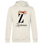 Ein cremefarbener Hoodie mit einem weihnachtlichen „Z“-Design in Schwarz, verziert mit einem Weihnachtsmann-Hut und Rentiergeweihen, an denen bunte Kugeln hängen. Unter dem Buchstaben steht der Name „Zacharias“ in eleganter, geschwungener Schrift. Der Hoodie strahlt eine festliche und personalisierte Stimmung aus, perfekt für die Weihnachtszeit.