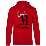 Ein roterr Hoodie mit einem festlichen Design. Der Buchstabe „M“ wird von einer Weihnachtsmütze und Rentiergeweihen geschmückt, an denen bunte Christbaumkugeln hängen. Darunter steht der Name „Matthias“ in eleganter, geschwungener Schrift. Dieser personalisierte Hoodie strahlt weihnachtliche Stimmung aus und eignet sich perfekt als individuelles Geschenk für die Feiertage.