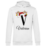 Ein weißer Hoodie mit einem weihnachtlichen Design, das den Buchstaben „V“ in Schwarz zeigt. Der Buchstabe ist mit einem Weihnachtsmann-Hut und Rentiergeweihen verziert, an denen bunte Kugeln hängen. Unter dem Buchstaben steht der Name „Valerian“ in eleganter, geschwungener Schrift. Der Hoodie strahlt eine festliche und persönliche Note aus, perfekt für die Weihnachtszeit.