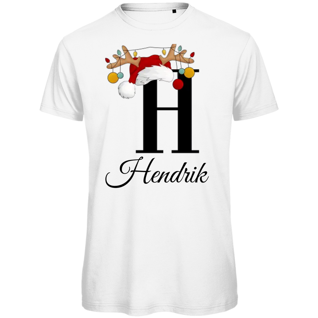 Ein weißes T-Shirt mit einem weihnachtlichen Design. Der große Buchstabe "H" ist mittig auf der Brust abgebildet und trägt einen Weihnachtsmann-Hut sowie Rentiergeweihe, an denen bunte Weihnachtskugeln hängen. Unterhalb des Buchstabens steht der Name "Hendrik" in eleganter, geschwungener Schrift. Das Design vermittelt eine festliche Stimmung und ist personalisiert für den Namen Hendrik.