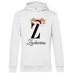 Ein weißer Hoodie mit einem weihnachtlichen „Z“-Design in Schwarz, verziert mit einem Weihnachtsmann-Hut und Rentiergeweihen, an denen bunte Kugeln hängen. Unter dem Buchstaben steht der Name „Zacharias“ in eleganter, geschwungener Schrift. Der Hoodie strahlt eine festliche und personalisierte Stimmung aus, perfekt für die Weihnachtszeit.