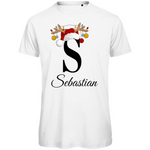 Ein weißes T-Shirt mit einem weihnachtlichen Design. Der große Buchstabe "S" ist mittig auf der Brust abgebildet und trägt einen Weihnachtsmann-Hut sowie Rentiergeweihe, an denen bunte Weihnachtskugeln hängen. Unterhalb des Buchstabens steht der Name "Sebastian" in eleganter, geschwungener Schrift. Das Design vermittelt eine festliche Stimmung und ist personalisiert für den Namen Sebastian.