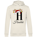 Ein cremefarbener Hoodie mit einem weihnachtlichen Design, das den Buchstaben "H" zeigt. Der Buchstabe ist in Schwarz gehalten und mit einem Weihnachtsmann-Hut sowie Rentiergeweihen verziert, an denen bunte Kugeln hängen. Unter dem Buchstaben ist der personalisierte Name "Hendrik" in eleganter, geschwungener Schrift zu sehen. Der Hoodie strahlt eine festliche und personalisierte Stimmung aus und eignet sich perfekt für die Winter- und Weihnachtszeit.