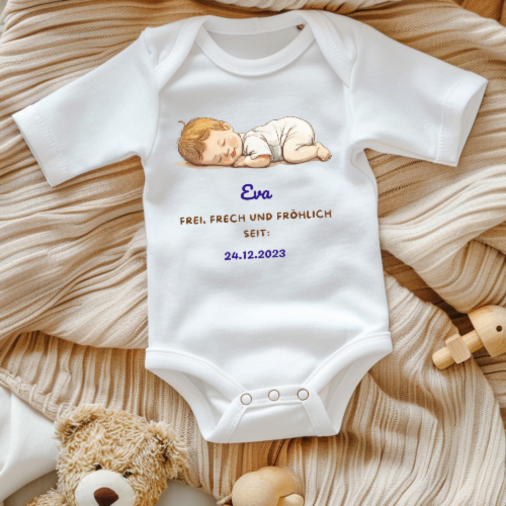 Ein weißer Baby-Body mit einem niedlichen Motiv eines schlafenden Babys. Darüber ist der Name 'Eva' in blauer Schrift zu sehen. Darunter steht der Text 'Frei, frech und fröhlich seit: 24.12.2023' in goldener und blauer Schrift. Der Body liegt auf einer beigen, gestrickten Decke und wird von Spielzeug umgeben, was eine warme und gemütliche Stimmung vermittelt. Ein perfektes, personalisiertes Geschenk zur Geburt.