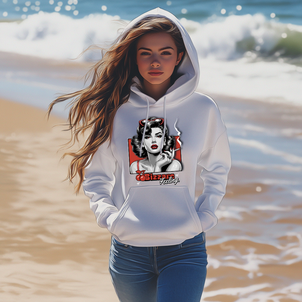 Eine Frau am Strand, die einen weißen Hoodie trägt. Auf dem Hoodie ist ein auffälliges Retro-Design mit einer stilisierten Frau im Vintage-Look zu sehen, umrahmt von einem roten Hintergrund. Darunter steht der Text 'Bizarre Feeling' in dekorativer Schrift. Die Szene wirkt modern und lässig und der Hoodie strahlt einen Hauch von Nostalgie und Individualität aus.