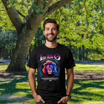 Ein Mann steht in einem sonnigen Park und trägt ein schwarzes T-Shirt mit einem astrologischen Design für das Sternzeichen Löwe (Leo). Das Motiv zeigt einen majestätischen Löwenkopf in leuchtenden, neonartigen Farben, umgeben von einem kreisförmigen, abstrakten Muster. Oben ist der Schriftzug 'Leo' in lila und pink zu sehen, und darunter eine Beschreibung der typischen Eigenschaften des Sternzeichens.