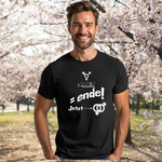 Schwarzes T-Shirt mit einer weißen Aufschrift, die verschiedene Symbole und Worte zeigt, darunter ein Transgender-Symbol, „: INNEN“, „= ende!“ sowie „Jetzt →“ mit einem Doppelpfeil, der auf ein Gender-Symbol verweist. Der Träger lächelt und steht vor einem Hintergrund voller blühender Kirschbäume.