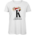 Ein weißes T-Shirt mit einem weihnachtlichen Design, das den Buchstaben 'K' zeigt. Der Buchstabe ist in Schwarz gehalten und mit einem Weihnachtsmann-Hut und Rentiergeweihen dekoriert, an denen bunte Kugeln hängen. Unter dem Buchstaben steht der Name 'Katharina' in eleganter, geschwungener Schrift.