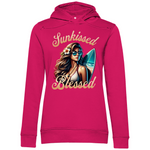 Ein pinker Hoodie mit dem Aufdruck „Sunkissed Blessed“. Der Druck zeigt eine stilvolle Frau mit langen, welligen Haaren, einer Sonnenbrille, einer Blume im Haar und einem Surfbrett im Hintergrund, während sie an einem sonnigen Strand steht. Ein lässiger und moderner Look, ideal für Strandliebhaber.