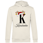 Ein cremefarbener Hoodie mit einem weihnachtlichen Design, das den Buchstaben "K" zeigt. Der Buchstabe ist in schwarz gehalten und mit einem Weihnachtsmann-Hut sowie Rentiergeweihen verziert, an denen bunte Kugeln hängen. Unter dem Buchstaben ist der personalisierte Name "Konstantin" in eleganter, geschwungener Schrift zu sehen. Der Hoodie strahlt eine festliche und personalisierte Stimmung aus und eignet sich perfekt für die Winter- und Weihnachtszeit.