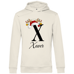 Cremefarbener Hoodie mit einem weihnachtlichen „X“-Design in Schwarz, verziert mit einem Weihnachtsmann-Hut und Rentiergeweihen, an denen bunte Kugeln hängen. Unter dem Buchstaben steht der Name „Xaver“ in eleganter, geschwungener Schrift. Der Hoodie strahlt eine festliche und personalisierte Atmosphäre aus, perfekt für die Weihnachtszeit.