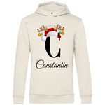 Ein cremefarbener Hoodie mit einem weihnachtlichen Design, das den Buchstaben "C" zeigt. Der Buchstabe ist in Schwarz gehalten und mit einem Weihnachtsmann-Hut sowie Rentiergeweihen verziert, an denen bunte Kugeln hängen. Unter dem Buchstaben ist der personalisierte Name "Constantin" in eleganter, geschwungener Schrift zu sehen. Der Hoodie strahlt eine festliche und personalisierte Stimmung aus und eignet sich perfekt für die Winter- und Weihnachtszeit.