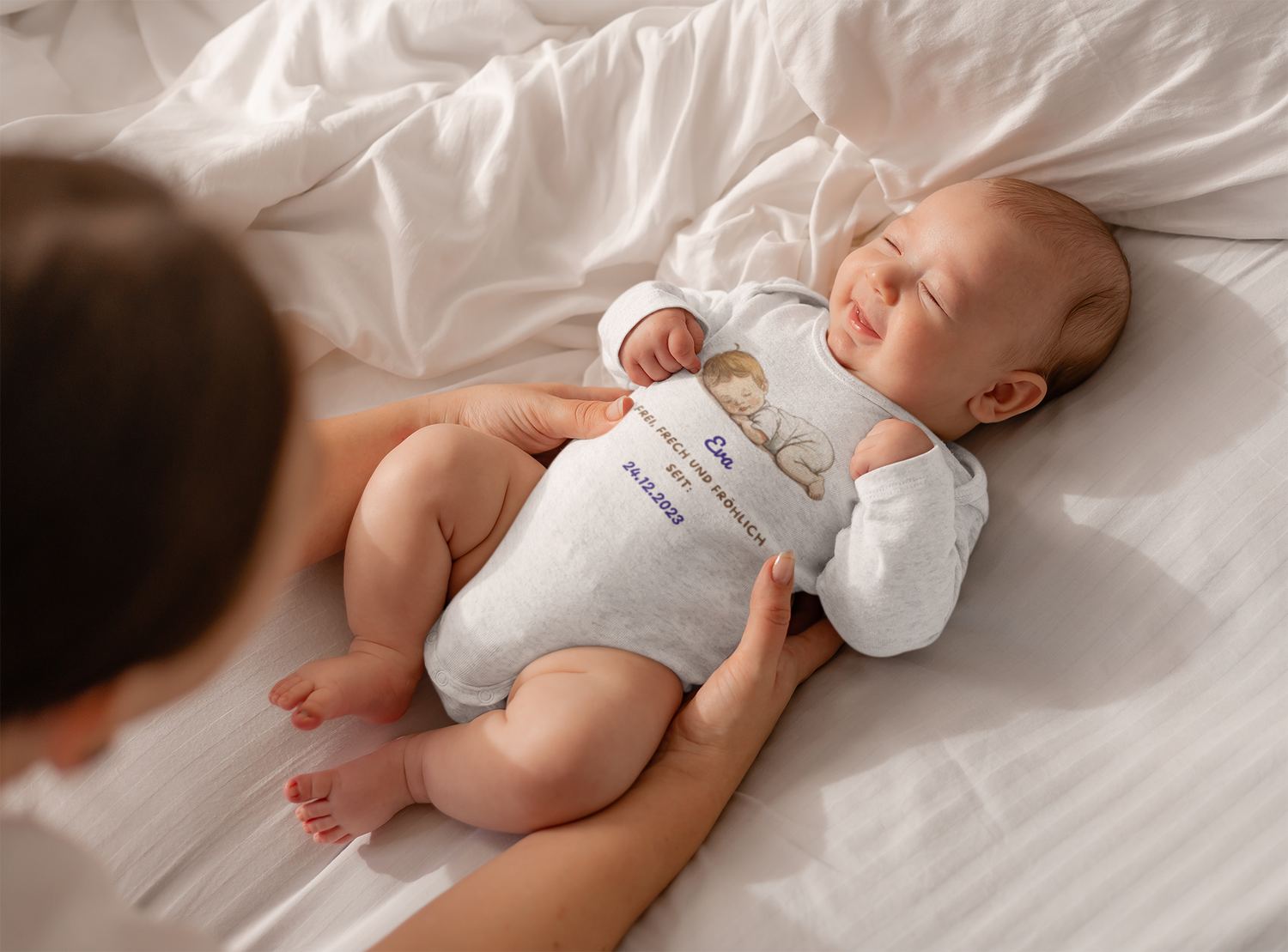 Langärmeliger weißer Baby Bio Body aus zertifizierter Bio-Baumwolle, personalisiert mit Namen und Geburtsdatum. Hautfreundlich und weich, mit Envelope-Ausschnitt und nickelfreien Druckknöpfen, ideal für empfindliche Babyhaut. Verfügbar in Größen von 0/3 Monaten bis 12/18 Monaten.