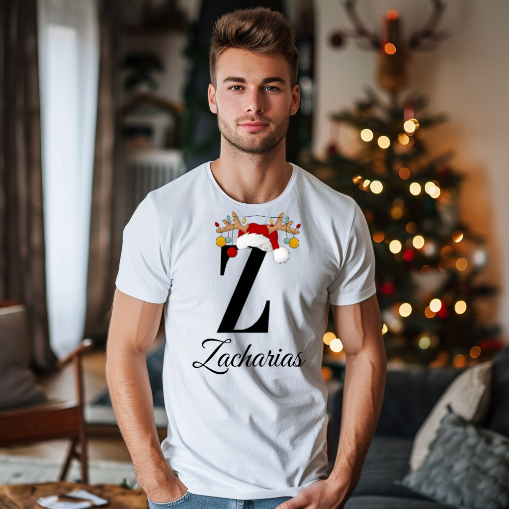 Ein weißes T-Shirt mit einem weihnachtlichen Design, das den Buchstaben „Z“ in schwarzer Farbe zeigt. Der Buchstabe ist mit einem Weihnachtsmann-Hut und Rentiergeweihen verziert, an denen bunte Kugeln hängen. Unter dem Buchstaben steht der Name „Zacharias“ in eleganter, geschwungener Schrift. Der Mann trägt das T-Shirt in einem gemütlichen Wohnzimmer mit einem festlich dekorierten Weihnachtsbaum im Hintergrund, was die weihnachtliche Stimmung unterstreicht.