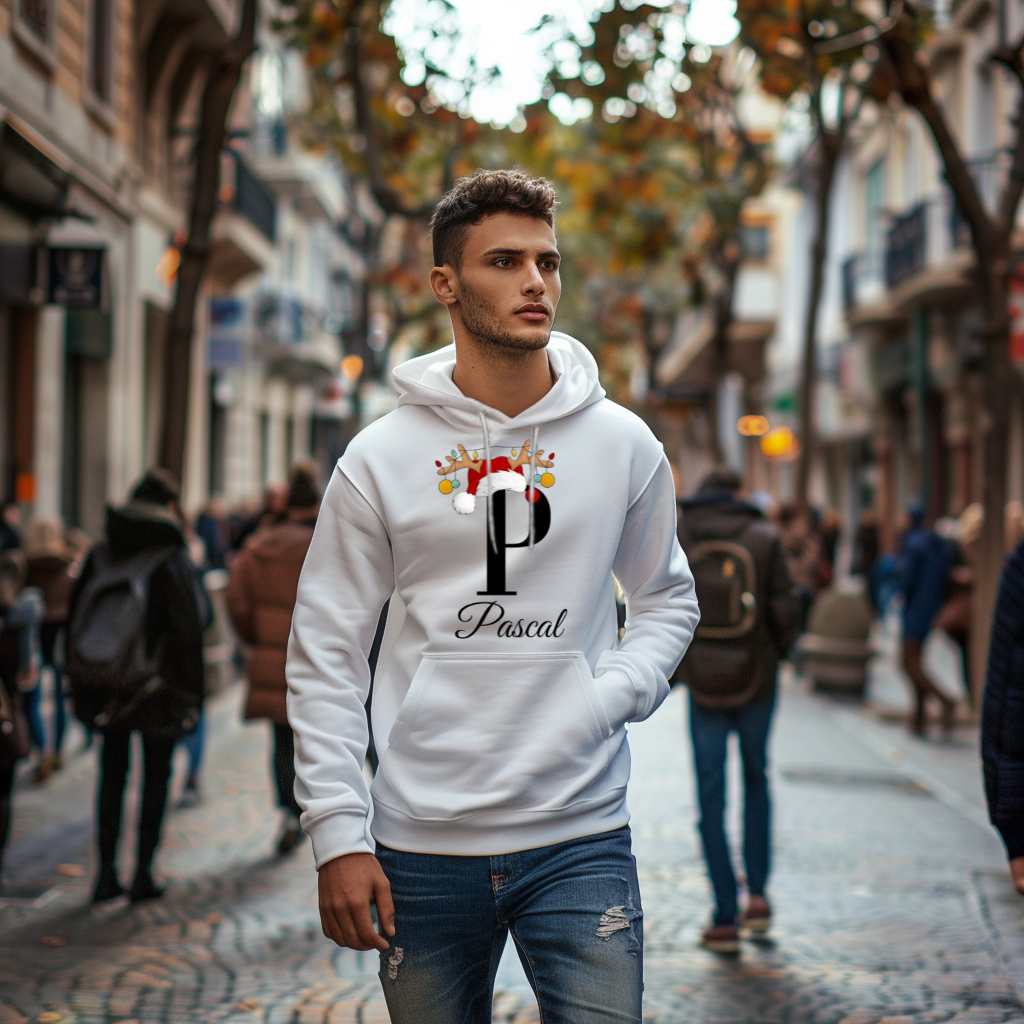 Das Bild zeigt einen jungen Mann, der auf einer belebten Straße einen weißen Hoodie trägt. Auf dem Hoodie ist der Buchstabe „P“ in Schwarz abgebildet, verziert mit einer Weihnachtsmütze und einem Rentiergeweih, an dem bunte Kugeln hängen. Darunter steht der Name „Pascal“ in einer eleganten, geschwungenen Schrift. Der Hoodie strahlt eine festliche Stimmung aus und eignet sich perfekt für die Weihnachtszeit.