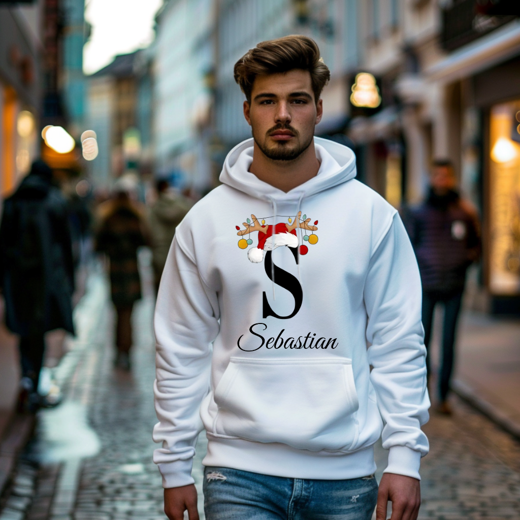 Ein weißer Hoodie mit einem weihnachtlichen Design, das den Buchstaben „S“ in Schwarz zeigt. Der Buchstabe ist mit einem Weihnachtsmann-Hut und Rentiergeweihen verziert, an denen bunte Kugeln hängen. Darunter ist der Name „Sebastian“ in eleganter, geschwungener Schrift abgebildet. Der Hoodie strahlt eine festliche und personalisierte Stimmung aus, perfekt für die Winter- und Weihnachtszeit.