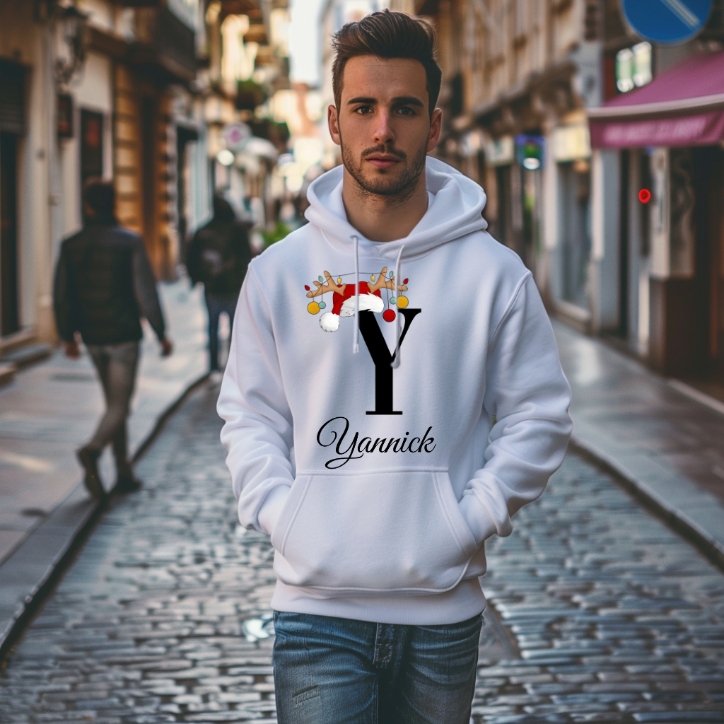 Ein weißer Hoodie mit einem weihnachtlichen „Y“-Design in Schwarz, verziert mit einem Weihnachtsmann-Hut und Rentiergeweihen, an denen bunte Kugeln hängen. Unter dem Buchstaben steht der Name „Yannick“ in eleganter, geschwungener Schrift. Der Hoodie strahlt eine festliche und personalisierte Atmosphäre aus, perfekt für die Weihnachtszeit. Der Träger geht durch eine städtische Straße, was eine lebendige und einladende Umgebung schafft.