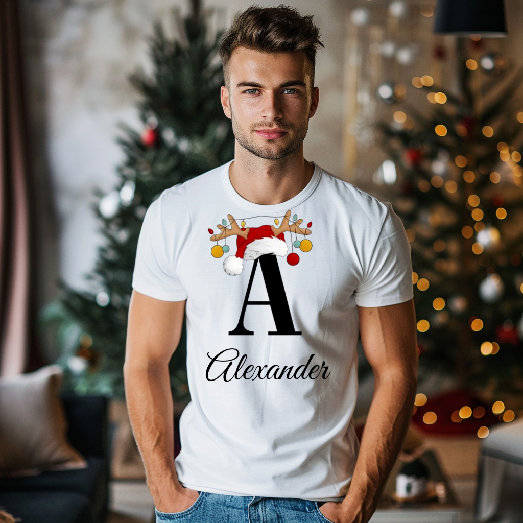 Ein weißes T-Shirt mit einem weihnachtlichen „A“-Design in Schwarz, verziert mit einem Weihnachtsmann-Hut und Rentiergeweihen, an denen bunte Kugeln hängen. Unter dem Buchstaben steht der Name „Alexander“ in eleganter, geschwungener Schrift, der personalisiert und nach Wunsch änderbar ist. Der Träger steht vor einem festlich geschmückten Weihnachtsbaum, was eine warme und festliche Atmosphäre schafft. Perfekt für die Weihnachtszeit und individuelle Namensgestaltung.