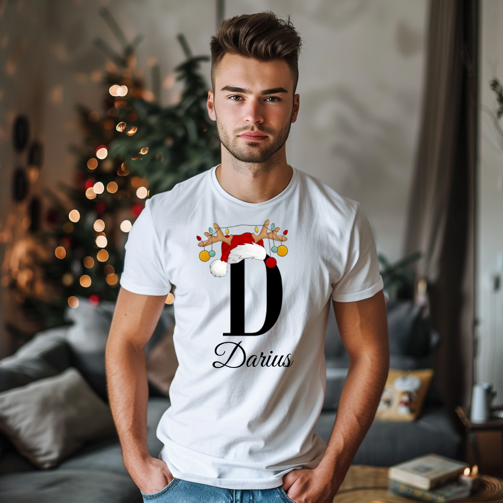 Ein weißes T-Shirt mit einem weihnachtlichen „D“-Design in Schwarz, verziert mit einem Weihnachtsmann-Hut und Rentiergeweihen, an denen bunte Kugeln hängen. Unter dem Buchstaben steht der Name „Darius“ in eleganter, geschwungener Schrift. Der Name ist personalisierbar, während die Schrift festgelegt bleibt. Der Träger steht in einem weihnachtlich dekorierten Raum mit einem festlich geschmückten Weihnachtsbaum im Hintergrund. Ideal für die Weihnachtszeit und individuelle Namensgestaltung.
